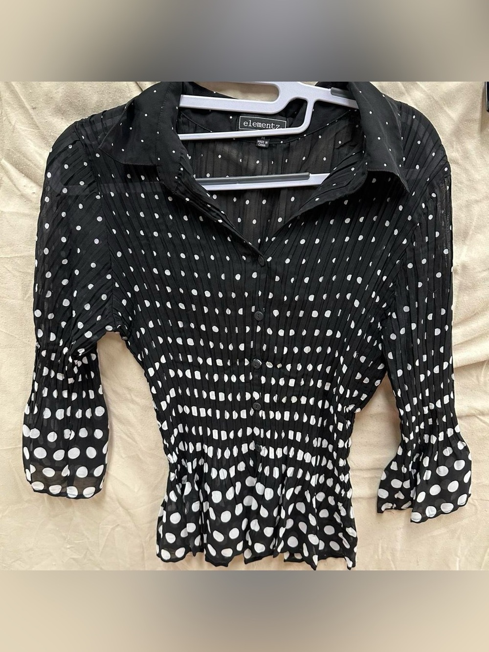 Black and white polka dot button up blouse with flare bottom and sleeves.